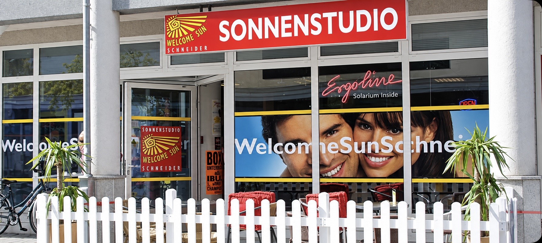 Außenansicht von WELCOME SUN Schneider mit rotem Sonnenstudio-Schriftzug in Wörgl