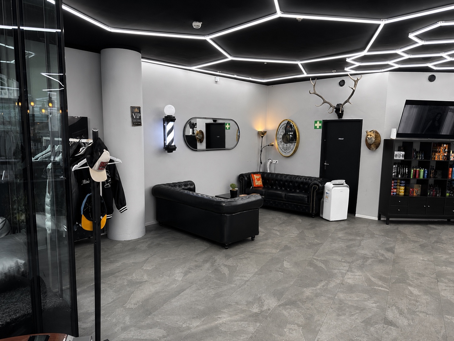 Wartebereich mit schwarzen Chesterfield-Ledersofas und Barber-Pole